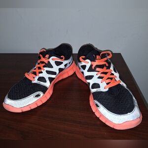 A pair of Nike Free Run 2. They Are Black With Orange Accents. Womens Size 6.5